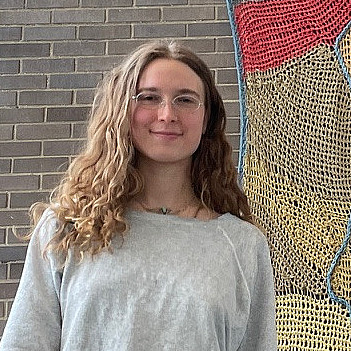 Rowan Perkins with her tapestry, A River to the Sky, in the Center for Media, Film, and Theater
