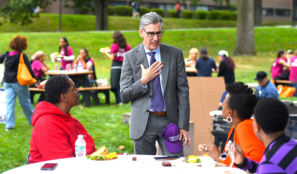 TalkingtoParents 2025 Man in suit stands speaking to adults sitting at a table turned toward him.