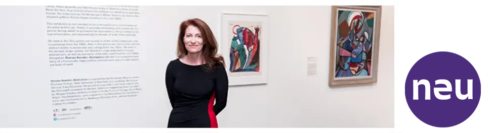 Who NEU Tracy Backstory Museum Director Tracy Fitzpatrick, a white woman with brown hair wearing a black dress standing in a gallery with colorful artwork